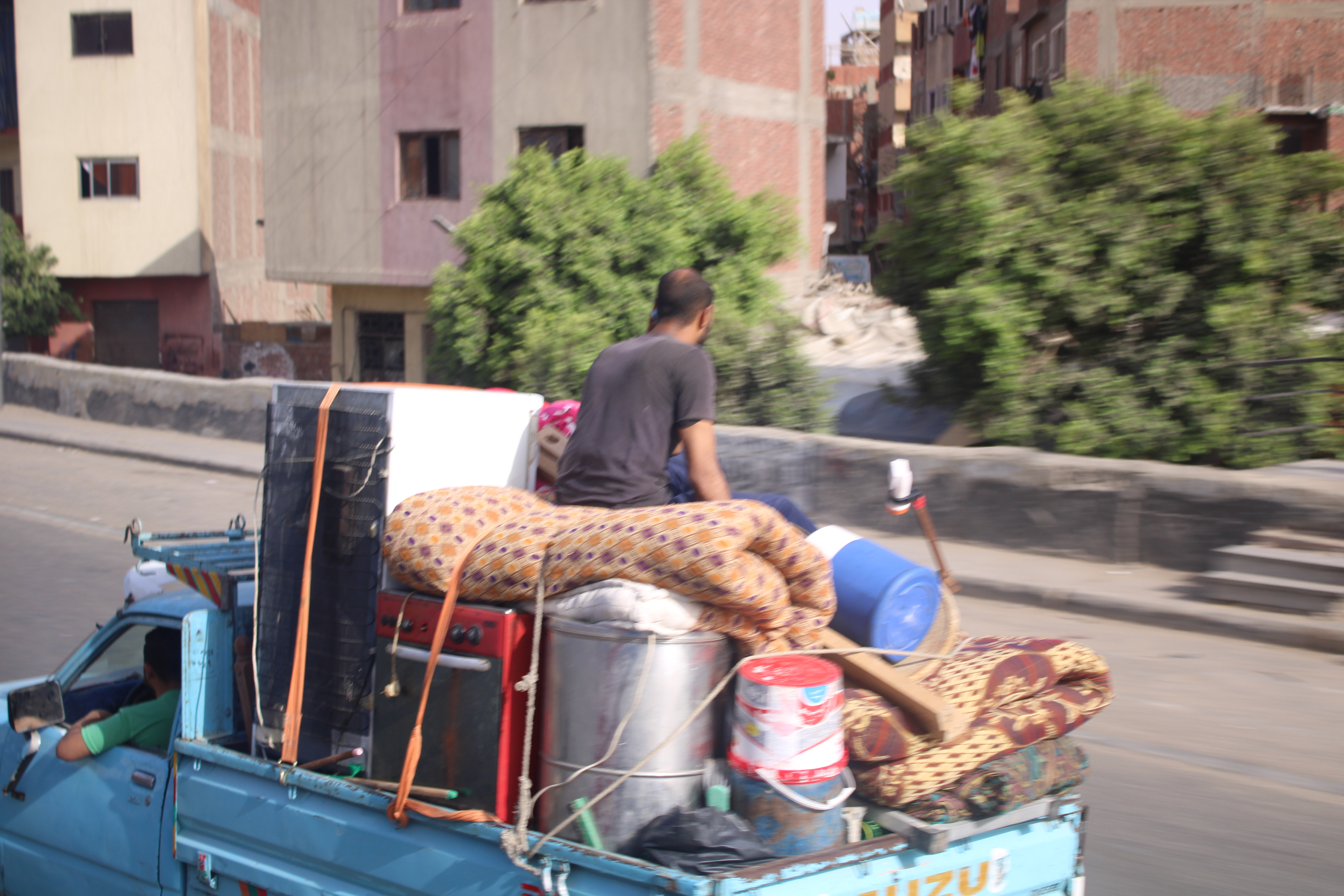 Homme assis sur un chargement à l'arrière d'une camionnette de déménagement.